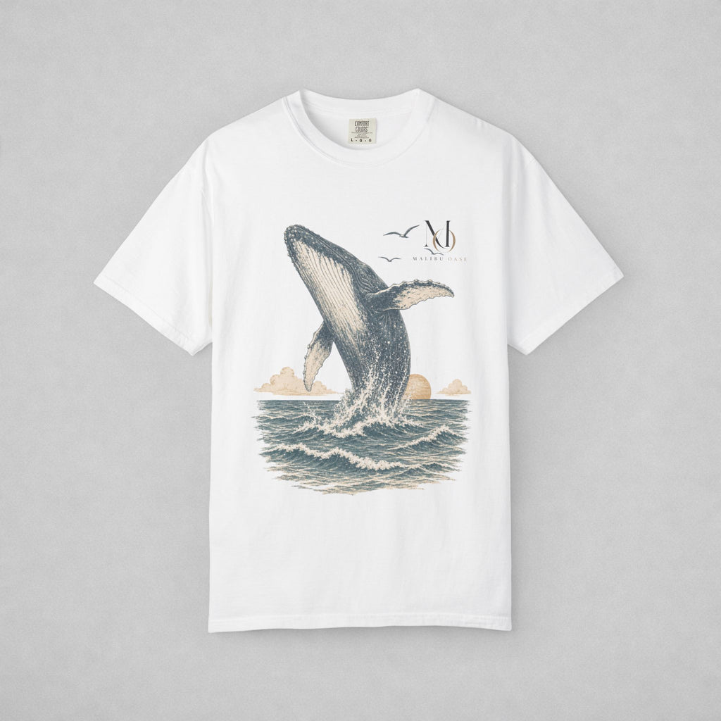 A white short-sleeve crewneck t-shirt featuring a vintage-style graphic print of a humpback whale breaching the ocean, with a sun, clouds, and birds, displayed flat against a neutral gray background.