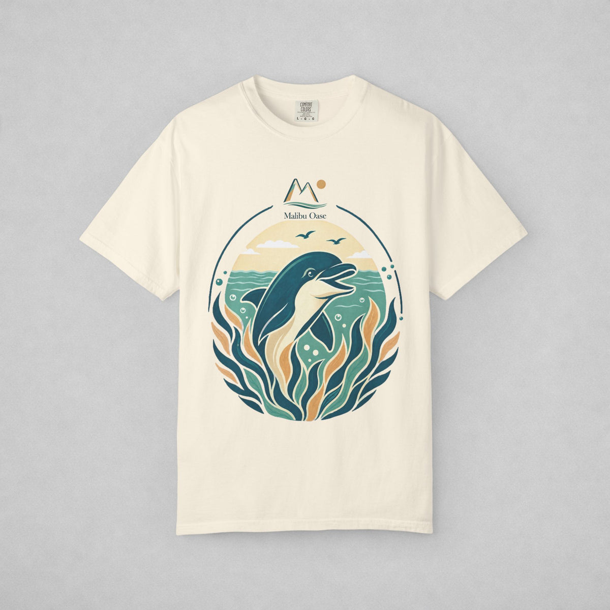 An off-white short-sleeve crewneck t-shirt with a circular graphic print of a dolphin, ocean waves, and the text 'Malibu Oase' on a light gray background.