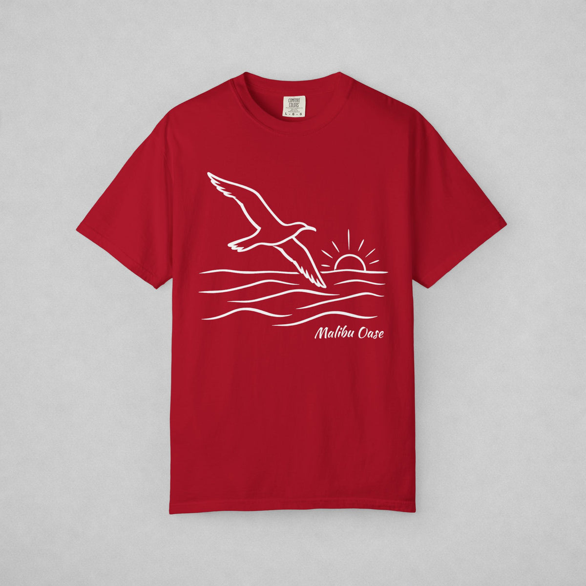 Red.  Short-sleeve t-shirt with a white line art graphic of a flying seagull, waves, a rising sun, and the text Malibu Oase' on the front, displayed flat against a neutral gray background.