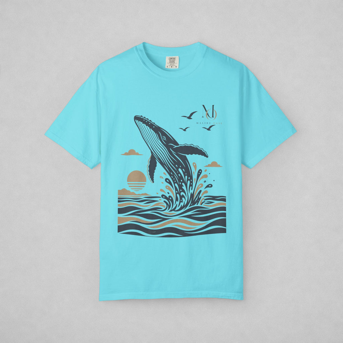 Lagoon Blue. Short-sleeve crewneck t-shirt with a graphic print of a whale jumping out of the water, birds, and a sun, displayed on a neutral gray background.