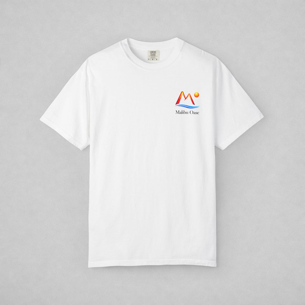 A white short-sleeve crewneck t-shirt with a small colorful 'Malibu Oase' graphic on the left chest, displayed flat against a neutral gray background.