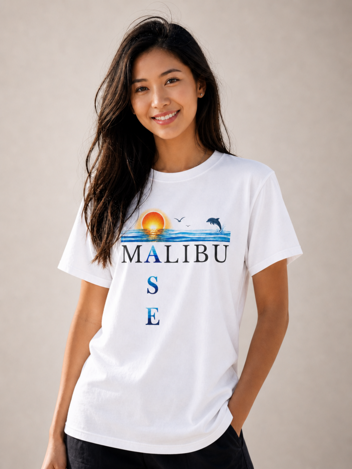 A woman wearing a white graphic t-shirt with a 'MALIBU OASE' design featuring a sunset and marine life, posed against a neutral beige background.