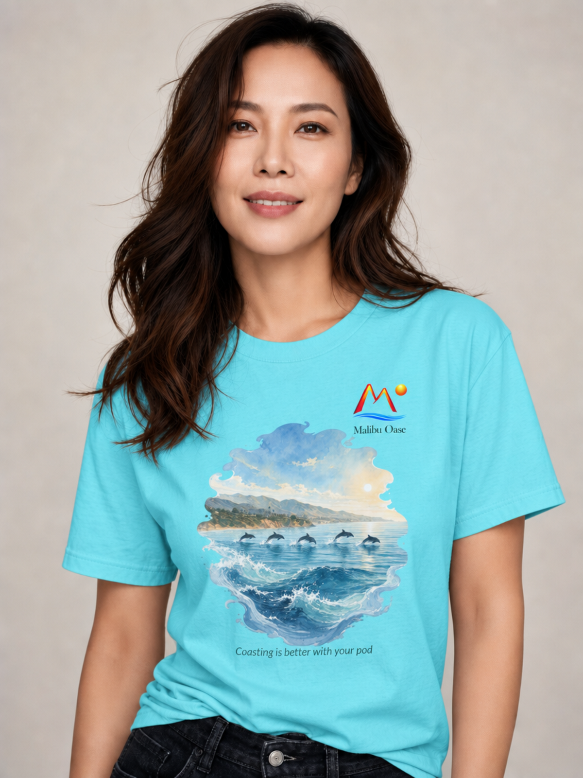 A woman wearing Lagoon Blue graphic t-shirt with a dolphin scene and the caption 'Coasting is better with your pod'.