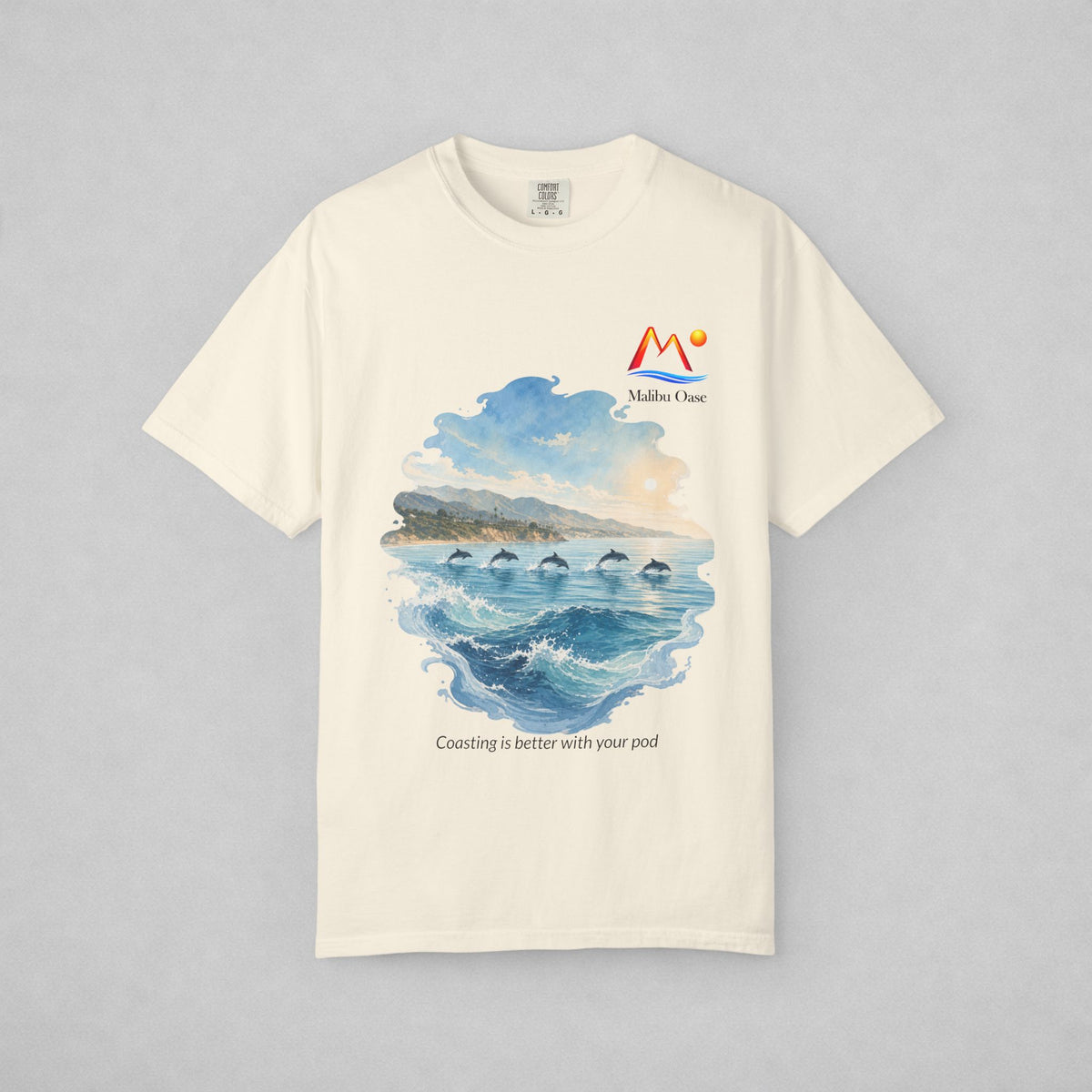 An Ivory short-sleeve crewneck t-shirt with a watercolor-style graphic of dolphins in the blue ocean, with the text 'Coasting is better with your pod'.
