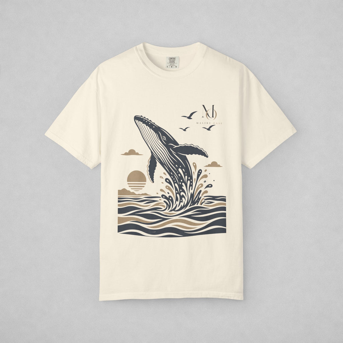 Ivory. Short-sleeve crewneck t-shirt with a graphic print of a whale jumping out of the water, birds, and a sun, displayed on a neutral gray background.