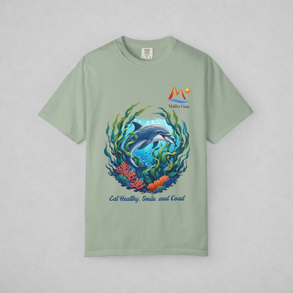 A sage green short-sleeve t-shirt with a colorful graphic of a dolphin swimming underwater with coral and seaweed, featuring the text 'Eat Healthy, Smile and Coast.'