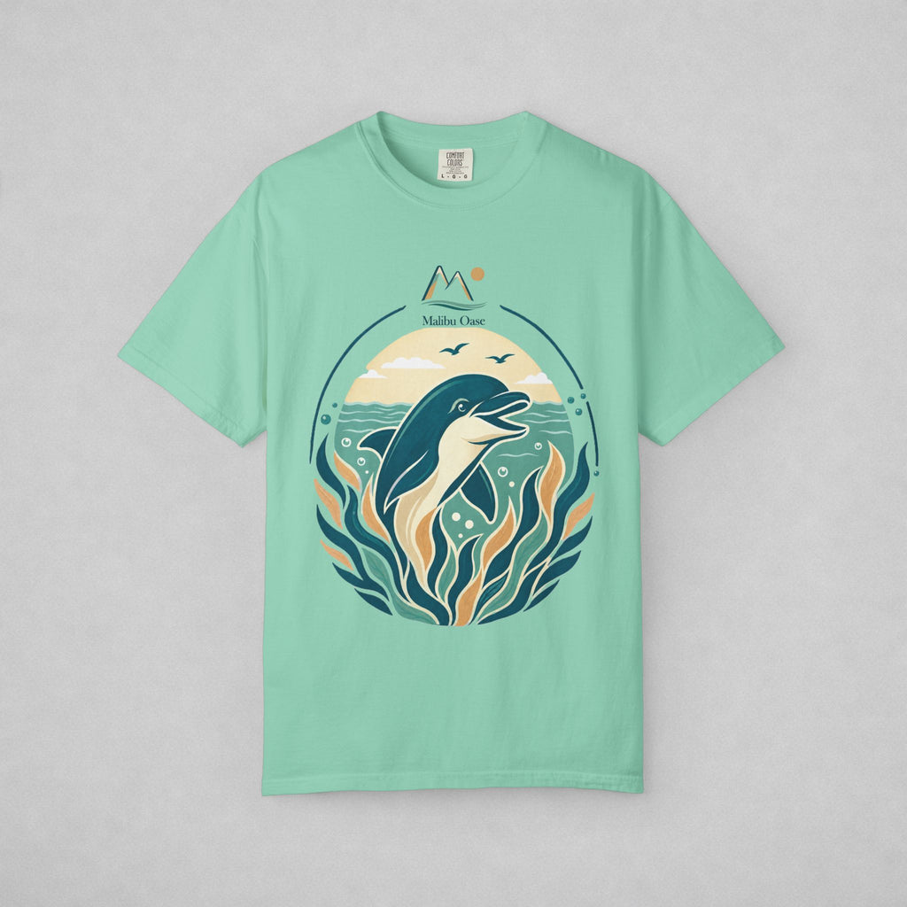 A mint green short-sleeve t-shirt with a circular graphic of a dolphin swimming among stylized kelp under a moon and stars, displayed flat against a light gray background.